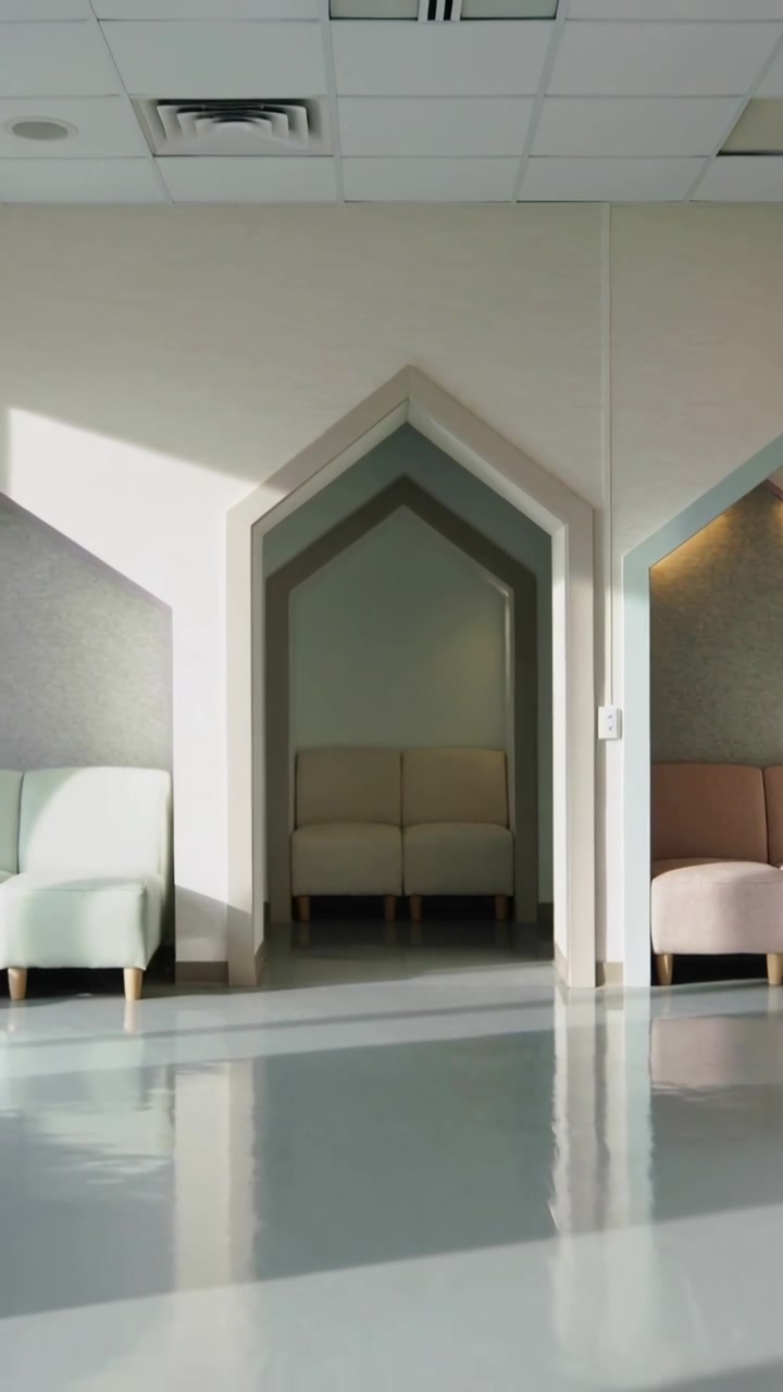 Video verticale: Telecamera che si allontana da un'inquadratura ravvicinata, mostrando una hall con nicchia ad arco e divano con sedute rosa menta.