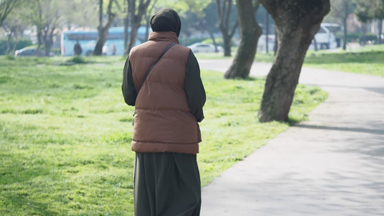 Person seen from behind walking on a path in a park