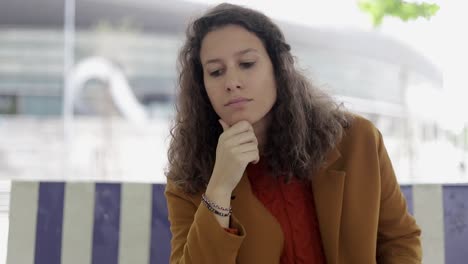 pensive young woman sitting on bench