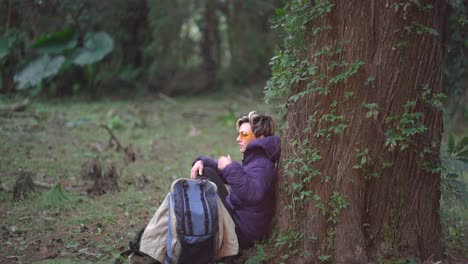 woman sitting against trunk in the outdoors