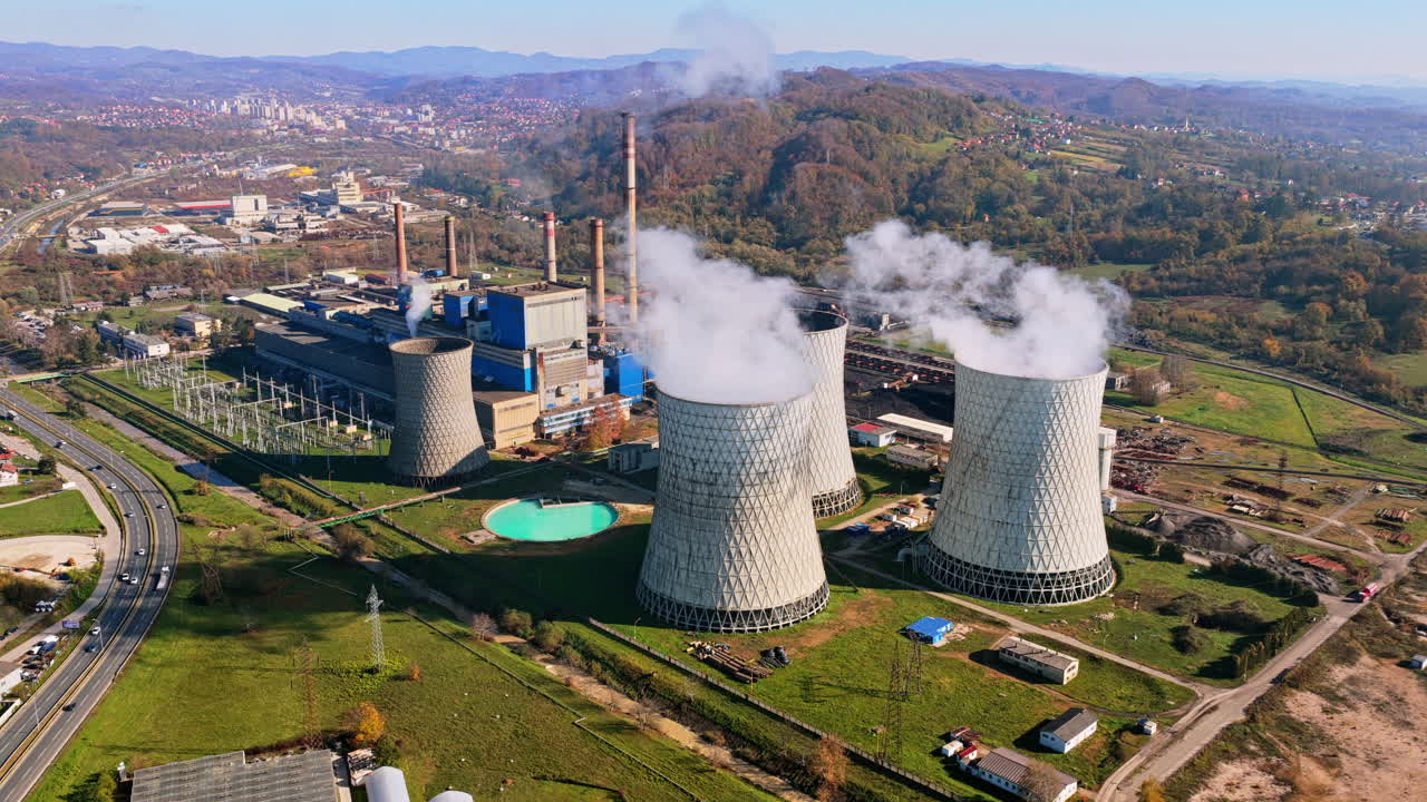 Aerial drone view of several large cooling towers releasing steam into the air at the Tuzla Power Plant