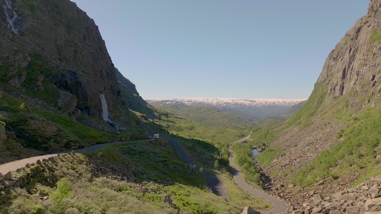 drone volando bajo sobre el viejo valle verde de la carretera de montaña rodeado de montañas escarpadas, noruega