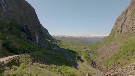 drone flying low over old mountain road verdant valley surrounded by rugged mountains, norway