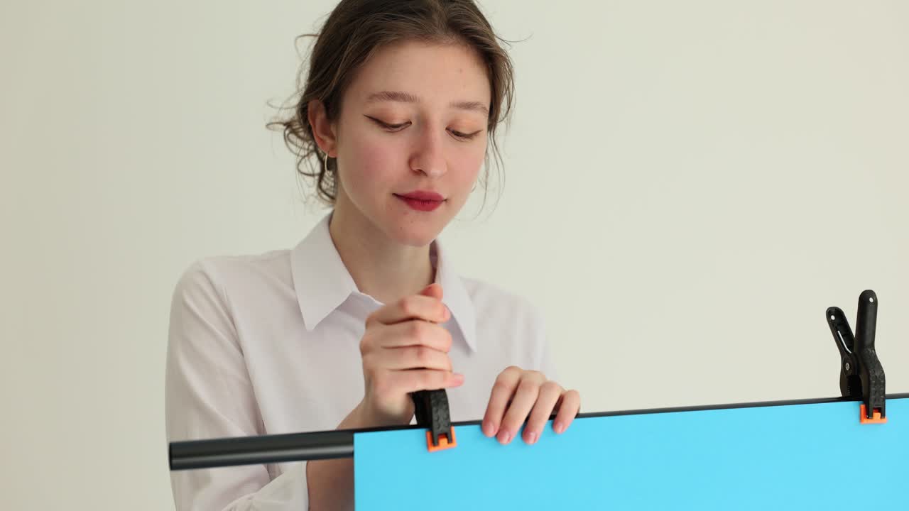 Giovane donna sistema un poster blu come sfondo per un video blog
