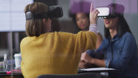 Diverse-work-colleagues-sitting-in-meeting-room-wearing-virtual-reality-glasses