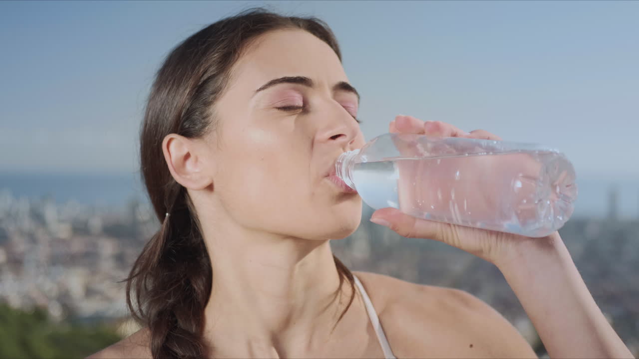 mujer abriendo una botella de agua en la calle. niña bebiendo agua después del entrenamiento de yoga