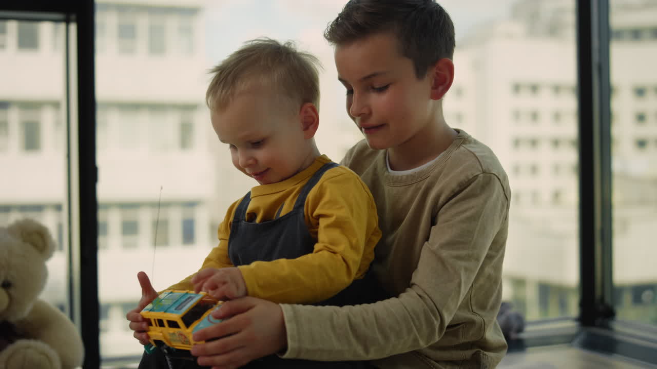 Younger brother sitting in older brother's laps on carpet