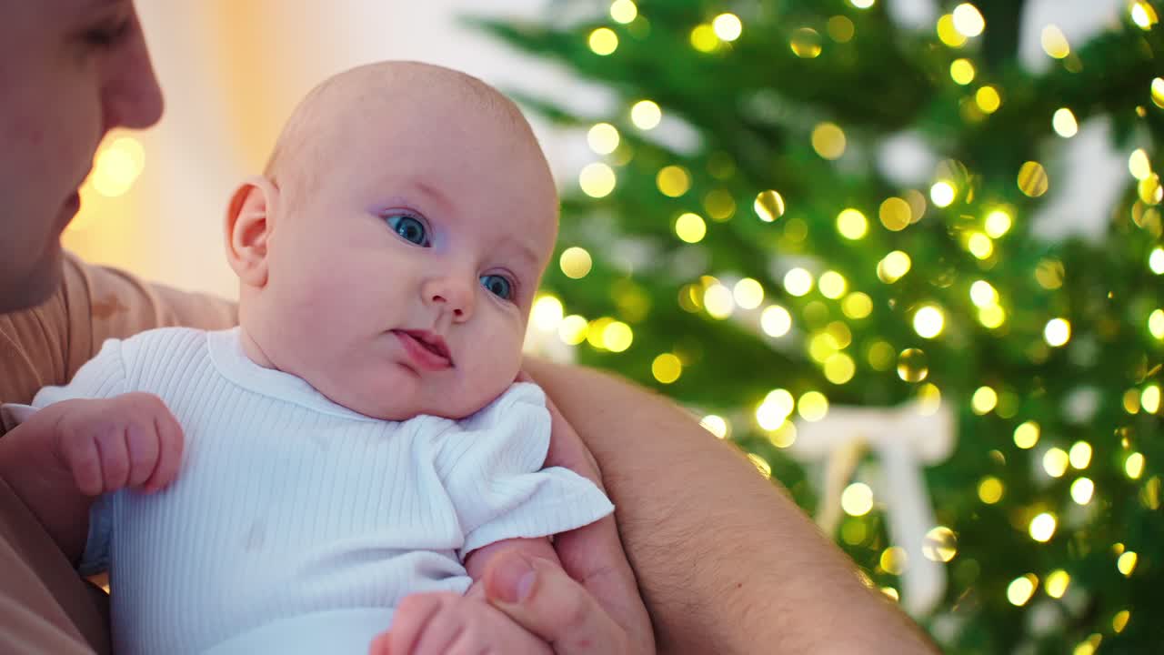 Vater hält Neugeborenes bei einem Weihnachtsbaum