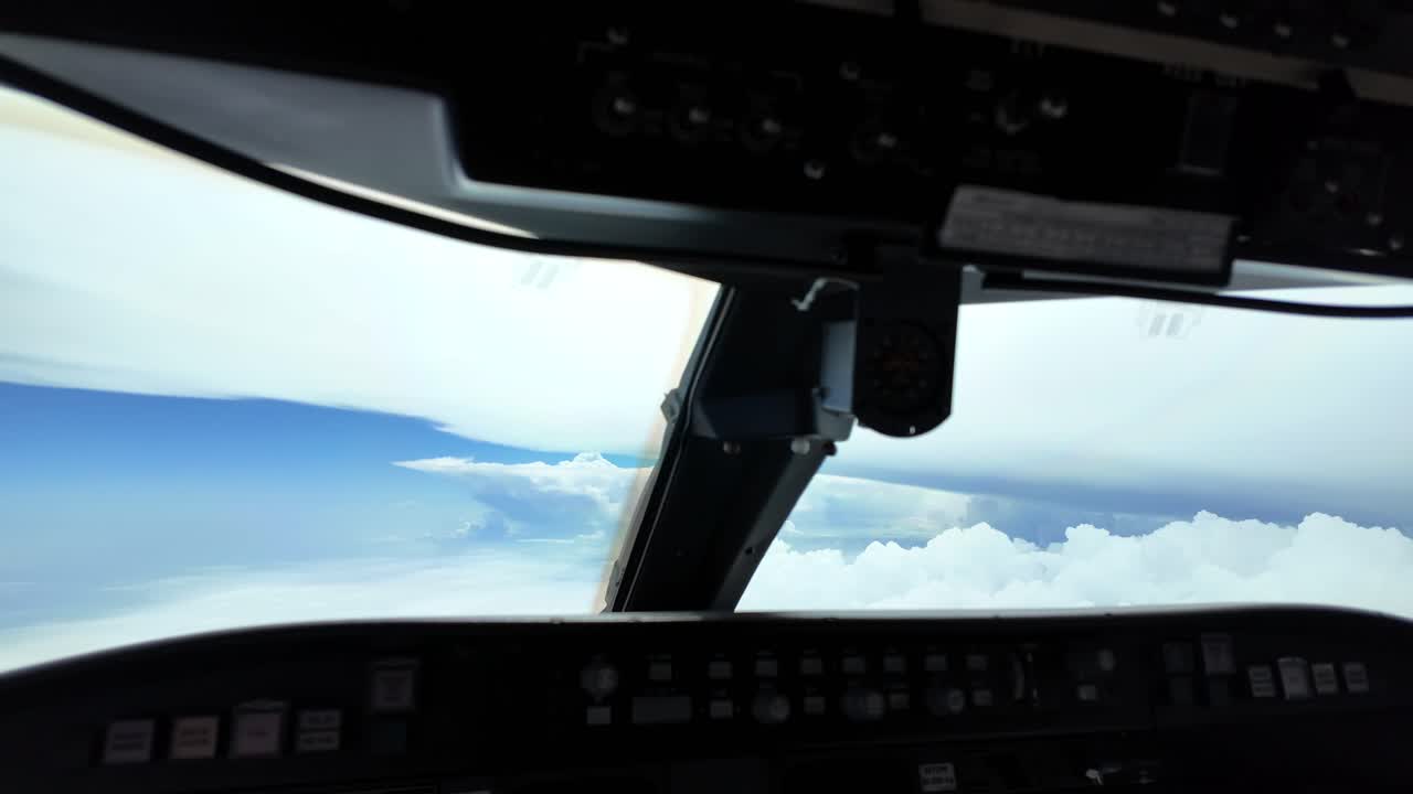 거대한 폭풍우 구름 근처에서 비행하는 동안 제트 조종사 의 조종사의 손이 손가락으로 폭풍우를 가리키고 있습니다.