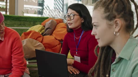 mujer de negocios confiada en ropa informal sosteniendo un panel táctil mientras se sienta en la mesa frente a dos colegas y presenta el nuevo plan 1