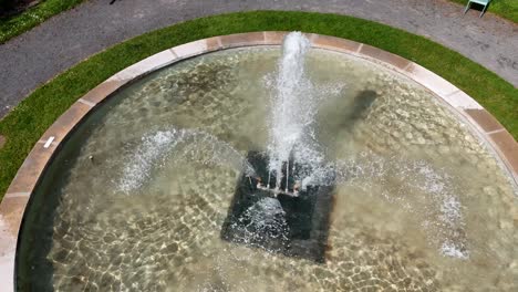 Aerial-view-of-a-rotating-fountain-in-le-parc-des-Capucins,-Coulommiers,-France