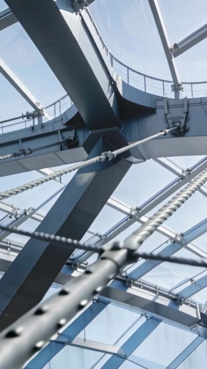 Vertical video: Panning camera revealing riveted tension rod in atrium roof, showing cable network
