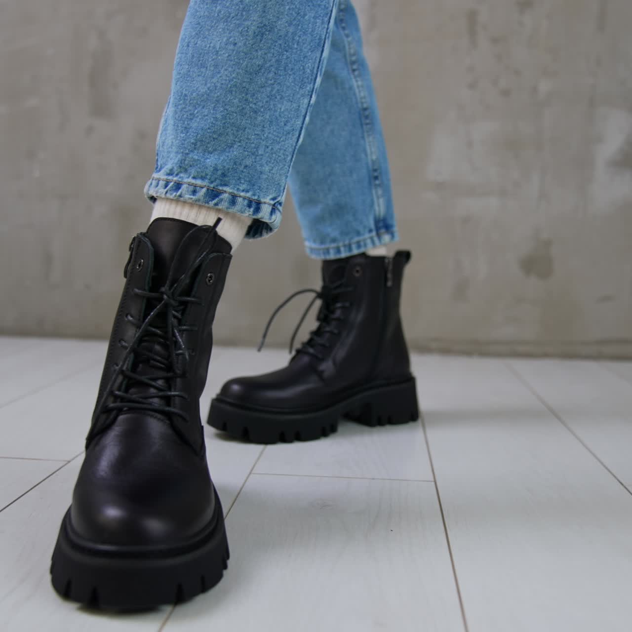 Model in jeans approaches camera and turns around. Low comfortable boots with laces demonstrated in studio. Close up