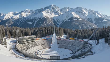 stunning panoramic view of a winter sports arena surrounded by majestic snow-capped mountains and pristine forests, capturing the essence of outdoor adventure and winter sports