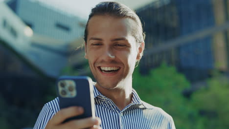 excited man reacting to good news on smartphone outdoors