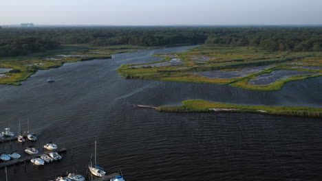 dolly-shot-forward---then-tilt-down-over-the-water---boats-on-the-pier-towards-the-marsh-area-at-sunset