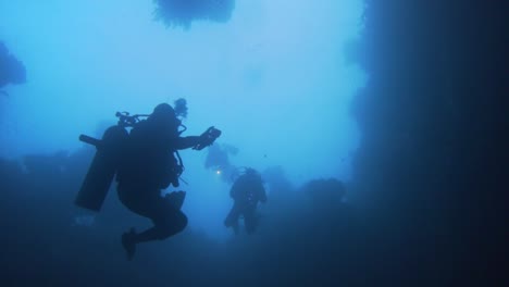 scuba divers diving into a underwater cave in misool, raja ampat