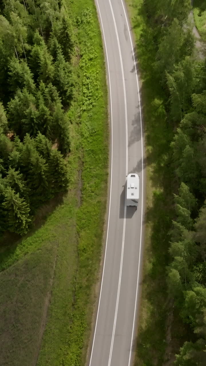 Vertical drone shot tilting over a camper van on a rural road, summer in Finland