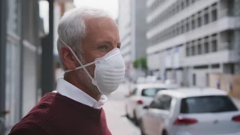 caucasian man out and about in the street wearing on a face mask against coronavirus