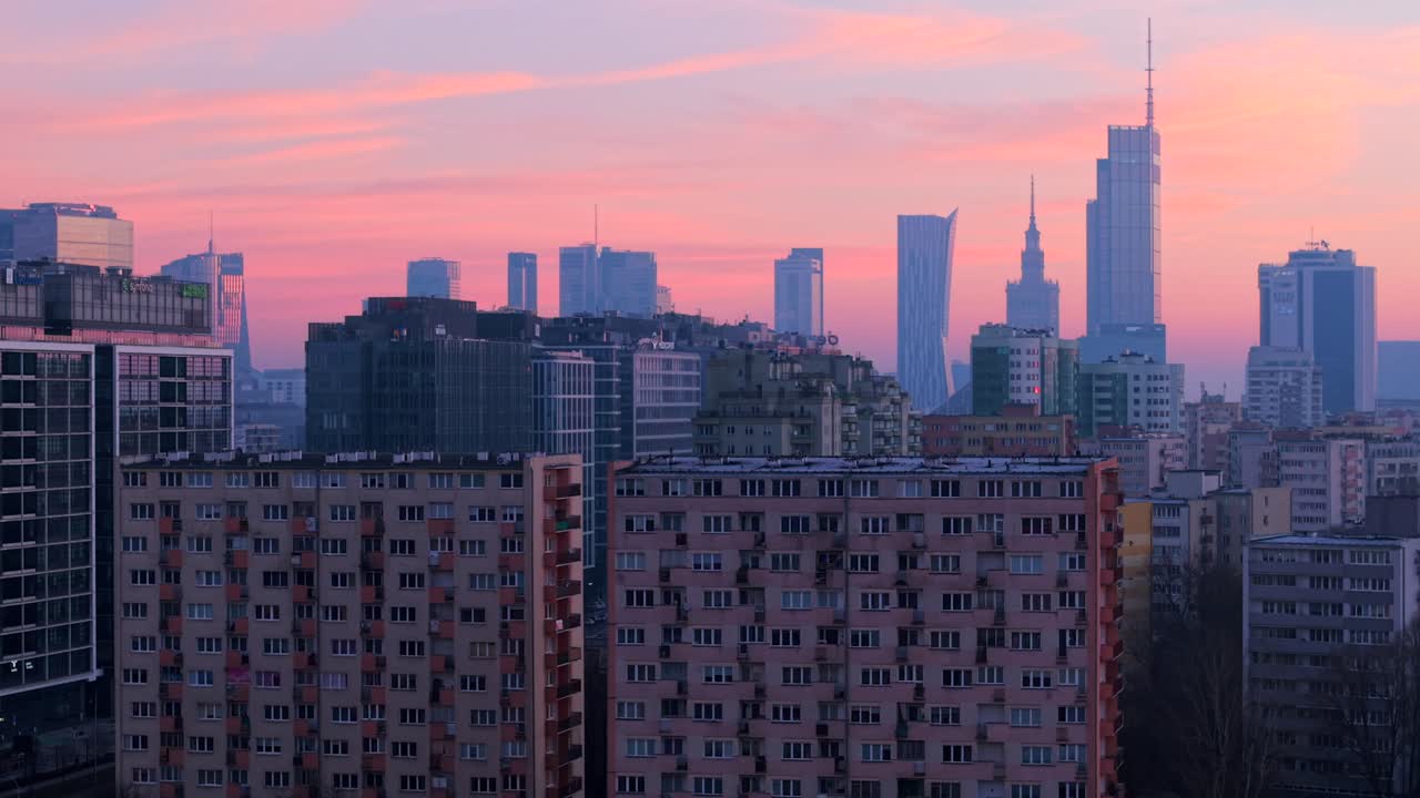 Drone shot of traditional concrete highrise residential buildings from 80s with Warsaw city neomodern financial institution skyscrapers in background in morning twilight, Establishing