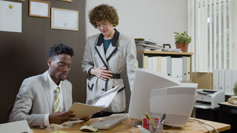 un hombre de negocios afroamericano usando una computadora retro en una oficina antigua.