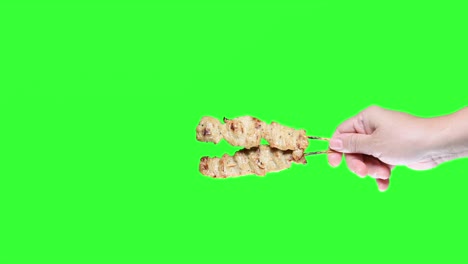 hand holding barbecued satay chicken on green screen background.