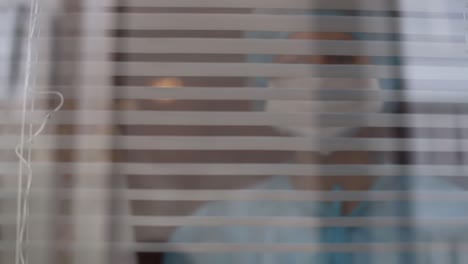 nurse looking through window of hospital with disturbed look, coronavirus (covid-19)