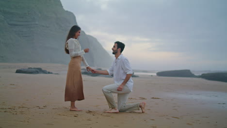 romantic man proposing marriage to woman at beach. couple celebrating engagement