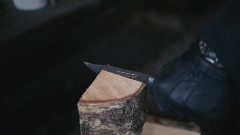 man cutting firewood with a knife in winter in lemmenlaakso, finland shot in120fps