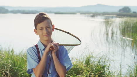 portrait of the nice teenage boy standing with a scoop net and smiling at the camera