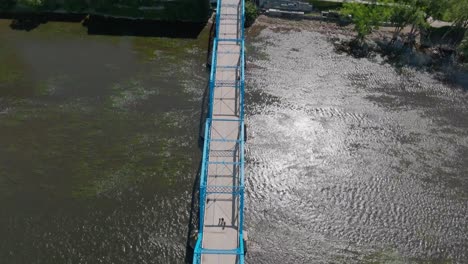 blue bridge over grand river in downtown grand rapids, michigan with drone video overhead and tilting up to skyline