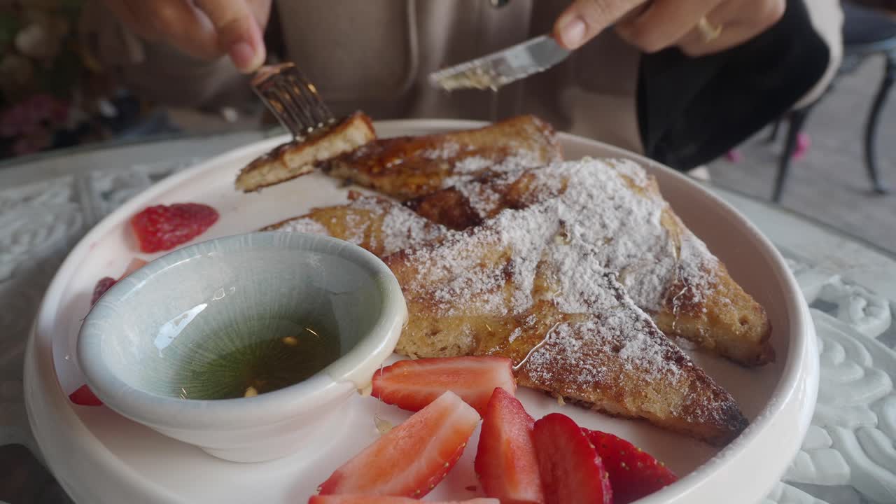 Woman eating French Toast with Strawberries and Honey