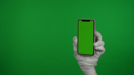 mummy hand holding smartphone with green screen on chroma key background