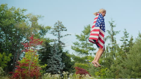 A-Woman-With-A-Flag-Of-The-Usa-Is-Jumping-On-A-Trampoline-Having-Fun-Independence-Day-And-A-Trip-To