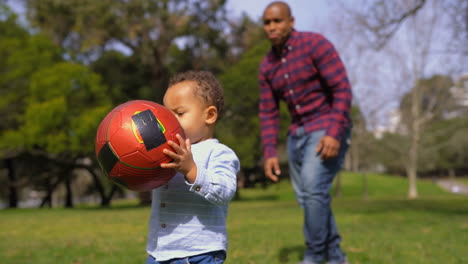 boy rising up ball from ground, running with it, falling down