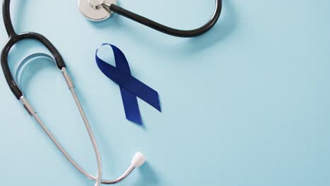 video of stethoscope and blue colon cancer awareness ribbon on blue background with copy space