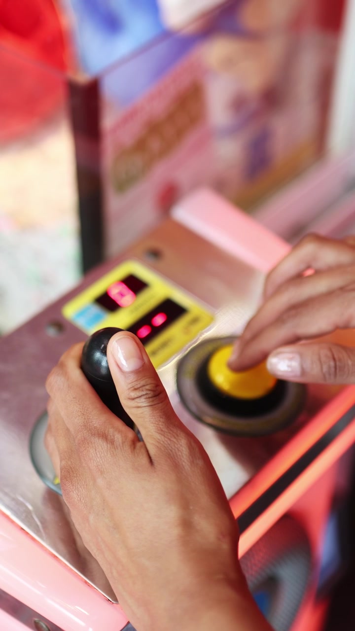 Mani che azionano una macchina a gru con joystick e pulsante giallo
