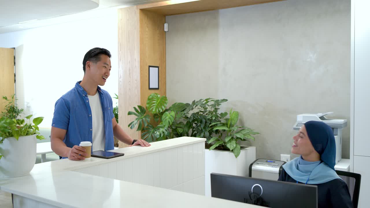 Asiatischer Mann, 30er, Tablet oder Kaffee, der auf die Uhr schaut, Visitenkarte am Schreibtisch an der Rezeption mit Hidschab