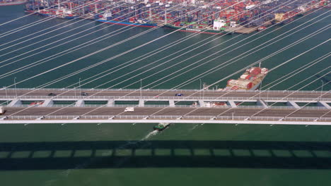 Revealing shot of Hong Kong container port behind suspension bridge with traffic