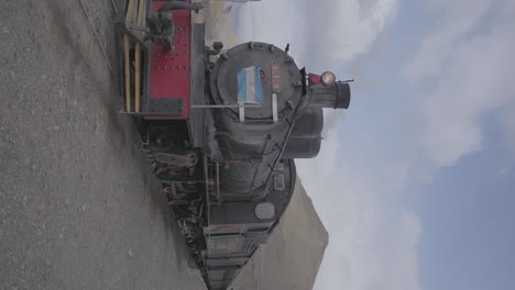 A-steam-railway-train-on-the-tracks-with-a-flag-of-Argentina-in-Patagonia-with-mountains-on-the-horizon