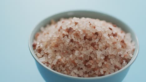 video of close up of bowl of organic salt on blue background