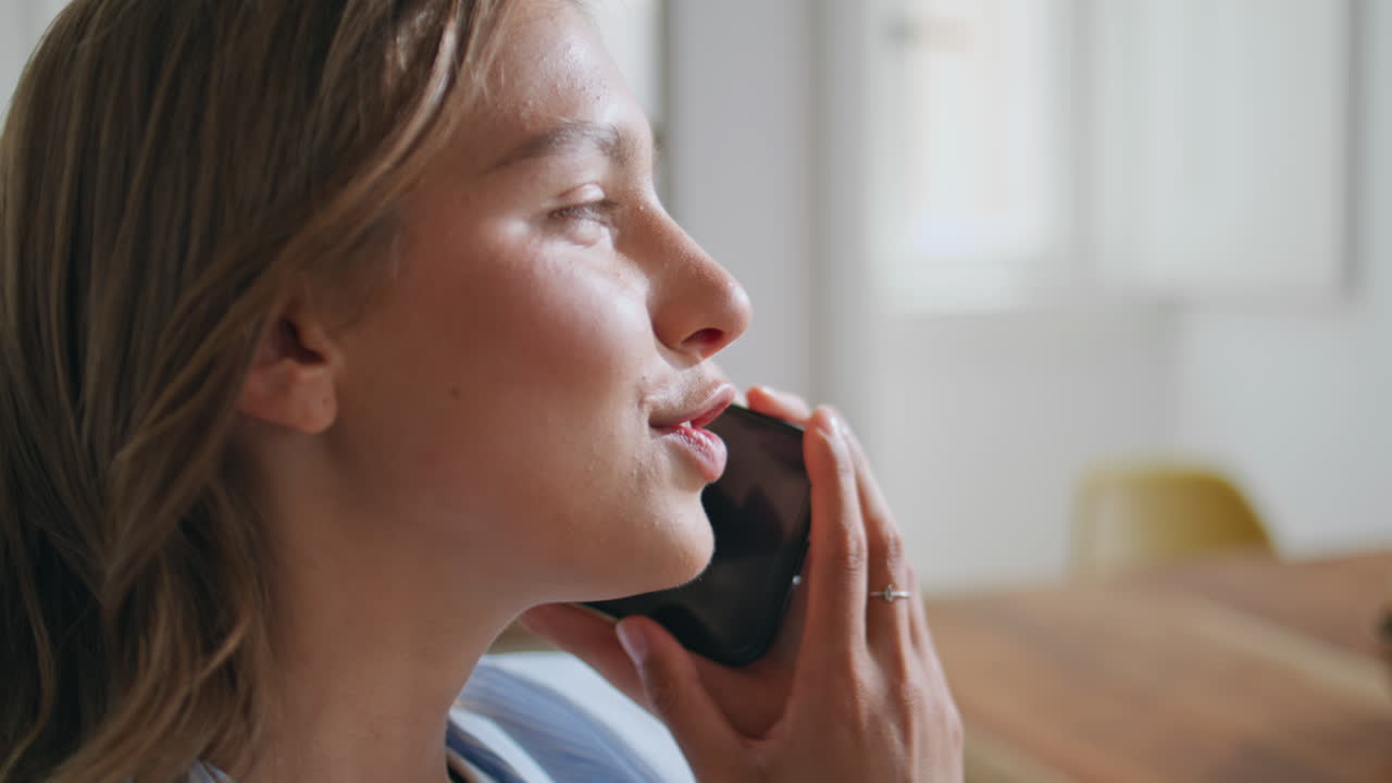 Carefree girl talking smartphone in sunny kitchen. Closeup happy lady end call