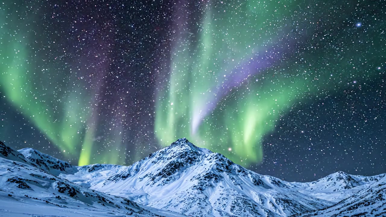 Viste mozzafiato dell'Aurora Boreale che illumina montagne innevate sotto un cielo stellato: uno spettacolo di luci naturali maestoso nel paesaggio artico.