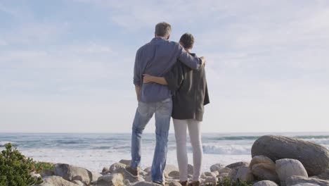 pareja caucásica disfrutando del tiempo libre en el mar en un día soleado abrazándose