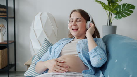 pregnant woman listening to music on couch