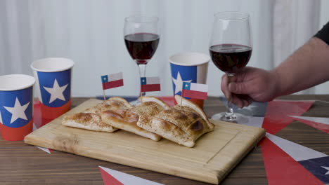 fiestas patrias chile putting up a wine glass empanada and chilean flags vertical