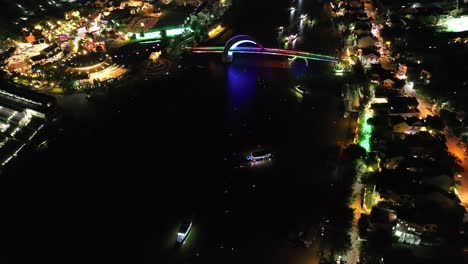 colorful bridge at night with boats on water and lively street lights in hoi an