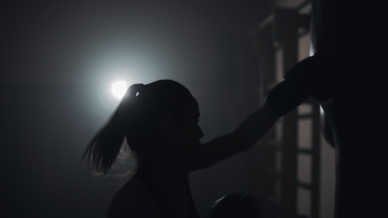 Woman Boxing Training in Dark Gym Silhouette