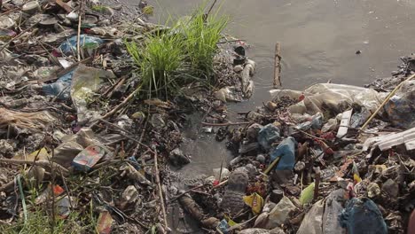 dumped garbage waste pollutes river water, global warming and environment issue