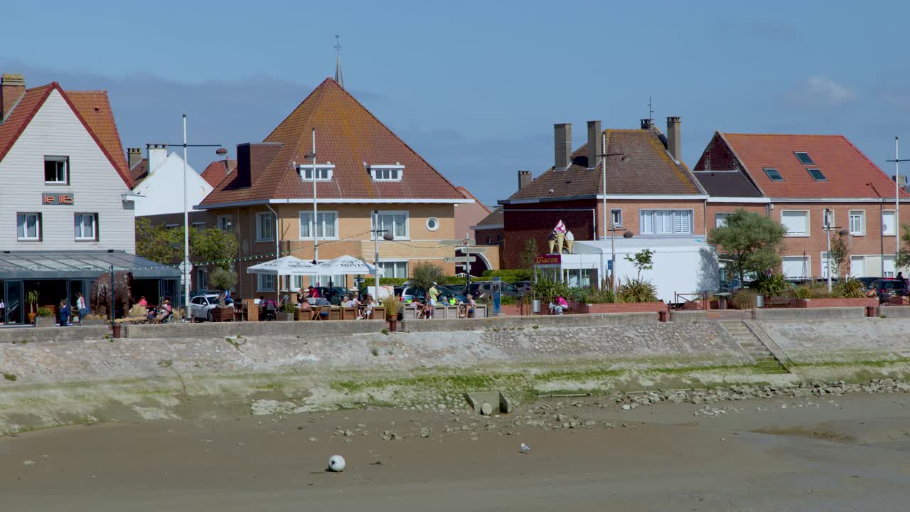 Camera pans across French coastal town, revealing houses, carousel, lighthouse, and sunny beach environment